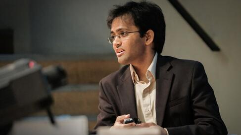 Man sitting at the front of a lecture theatre giving a presentation