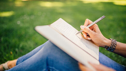 Person sitting outside writing in notebook