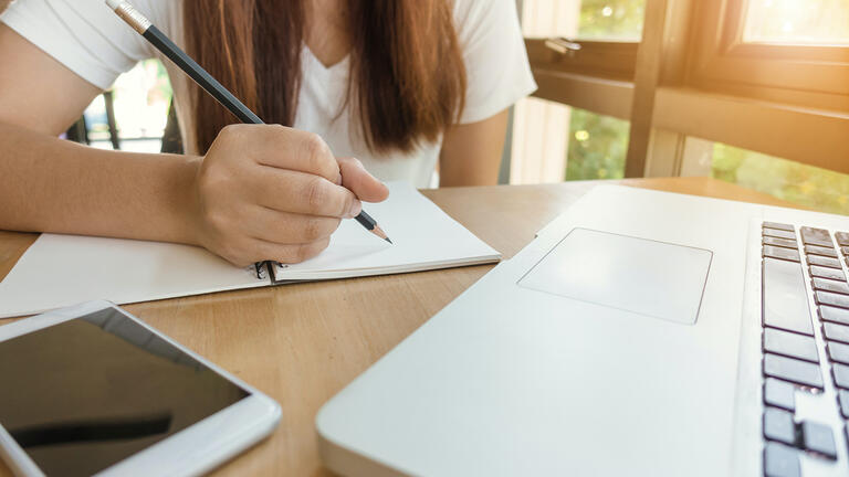 Woman working at computer with notebook