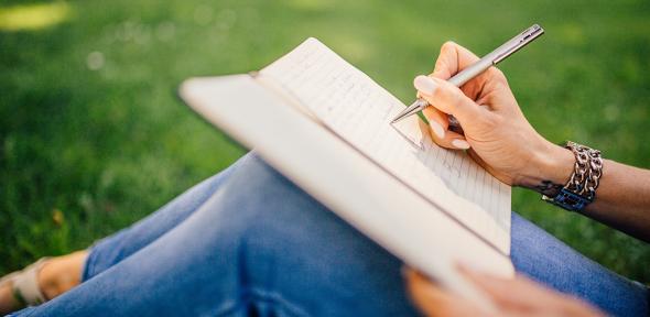 Person sitting outside writing in notebook